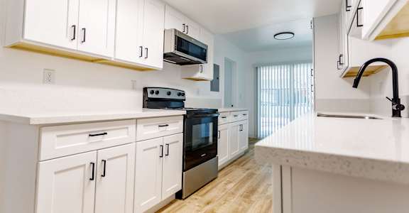A kitchen with white cabinets and a black oven.